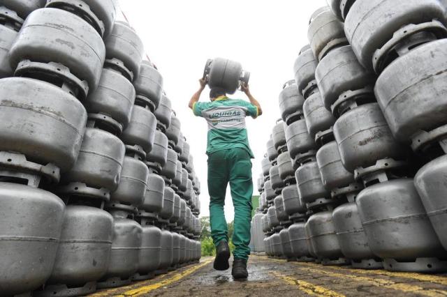 Entregador Liquigás carregando um botijão na unidade de distribuição